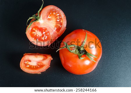 whole and sliced tomatoes on a black matte background
