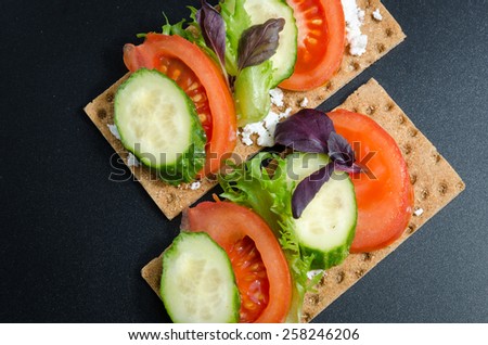 two crispy bread with tomato,cucumber and cottage cheese on a black matte background