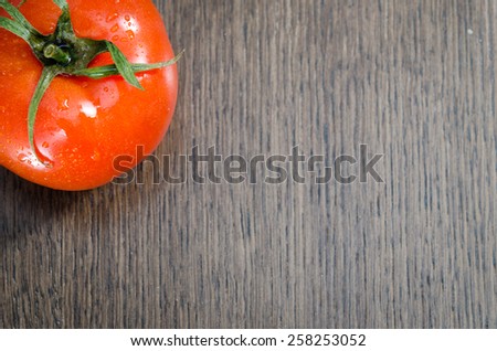 fresh tomato in the upper left corner on a brown background