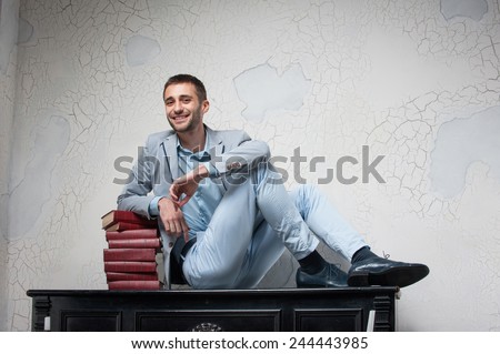 guy is preparing his final exams. smiling young man in a suit sits in a piano with books