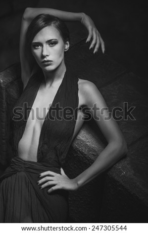 sexy elegant woman dressed in an evening dress. Stone on the background. monochrome image
