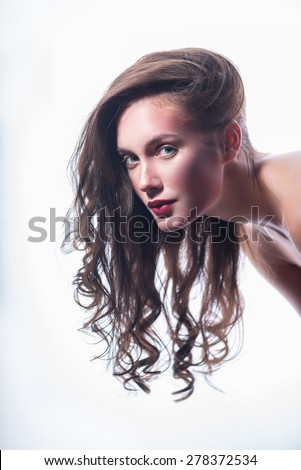 Young beautiful girl looks at the camera, long curly hair hanging down. isolate on white background