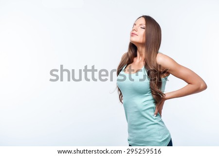 Attractive girl is standing with arms akimbo. She is resting and closing her eyes with pleasure. Isolated on background and copy space in left side