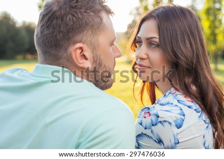 Forever together. Young attractive man and beautiful woman are looking at each other with love. They are sitting in park
