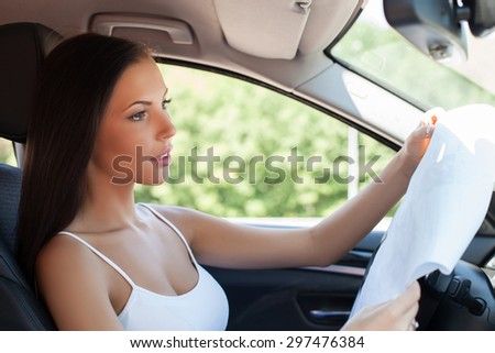 Cheerful woman is sitting in the modern transport. She is ready buying it. The lady is reading the papers seriously