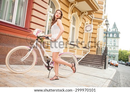 Beautiful woman is riding the bicycle and posing. She is looking aside mysteriously. The lady is flirting with someone. Copy space in right side