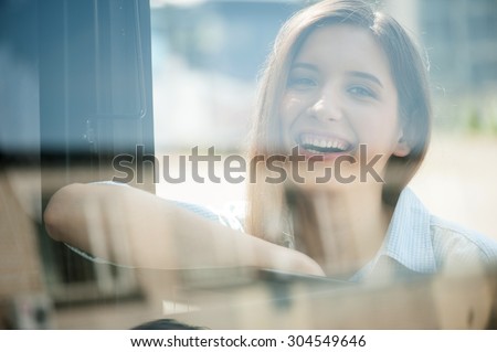 Beautiful woman is leaning on the handle of the bus and smiling. She is looking at the camera with joy