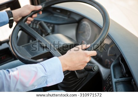 Close up of male hands. The driver is sitting at steering wheel of a bus