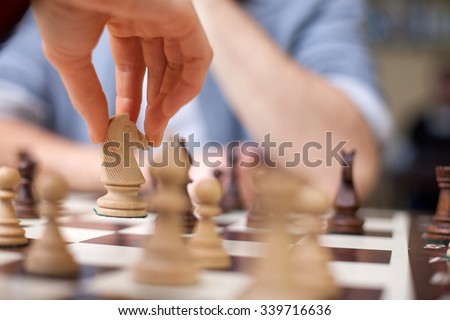 Close up of hands of young man and woman playing chess. They are sitting opposite each other
