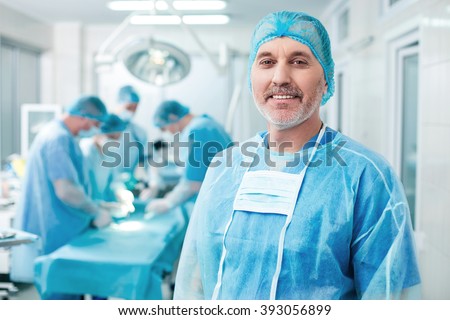 Cheerful old surgeon is examining the operation