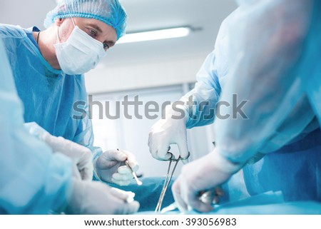 Experienced surgical doctor is operating on a patient