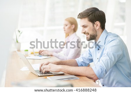 Cheerful male student is working on computer