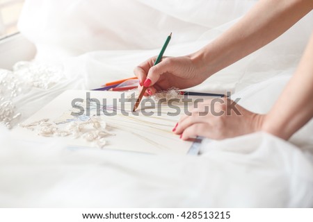 Cheerful female tailor is creating bridal gown