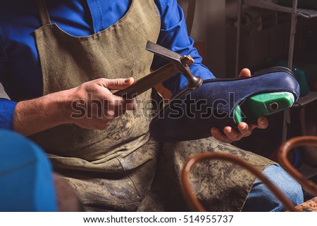 artisan holding a boot and hammer