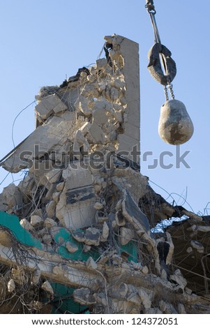 The remains of a demolished factory building, with wrecking ball hanging amidst the wreckage.