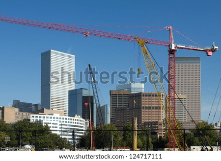 Large construction site in foreground, with the skyscrapers and building of Denver, Colorado in the background on a clear day.