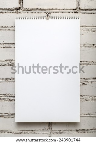Blank album on a spring against a white brick wall. Template for design calendars and photo albums. Vertical shot.