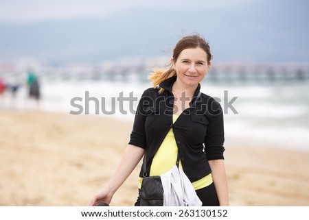 Smiling woman in a black blouse with a blurred background beach and sea.  Shallow depth of field. Focus on model.