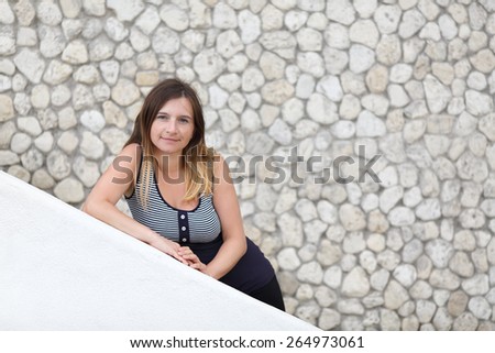 Pretty young woman with long hair posing on stained vintage background of stone wall. Shallow depth of field. Focus on the model\'s face. Space for text.