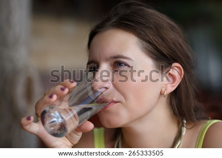 Cute young woman drinks water from a glass beaker. Shallow depth of field. Focus on the model\'s face.