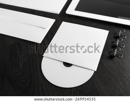 Blank compact disk on wooden table. Fragment of blank stationery and corporate identity template on dark background. Template for branding identity for designers. Shallow depth of field.