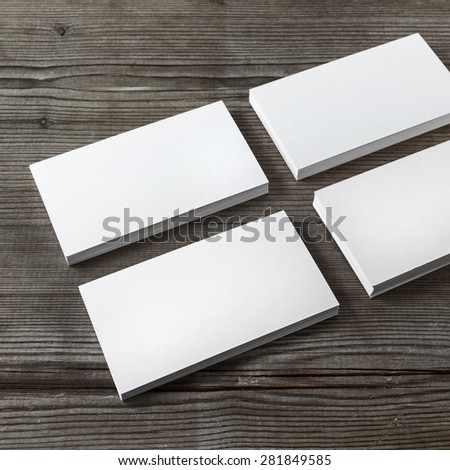 Set of blank white business cards on a dark wooden background. Template for branding identity. Shallow depth of field.