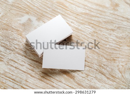 Blank business cards with soft shadows on light wooden background. Template for design presentations and portfolios. Studio shot.
