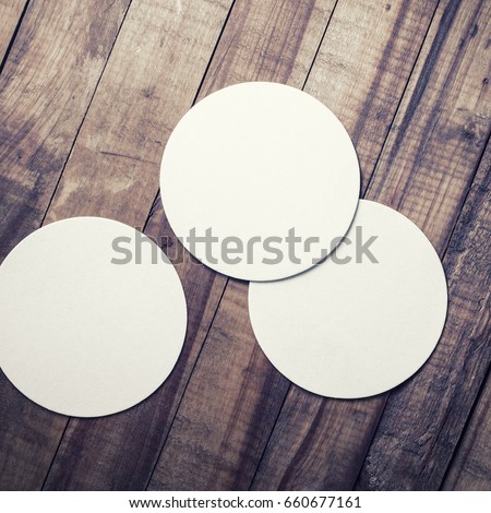 Three blank beer coasters on vintage wooden table background. Responsive design mockup. Top view.