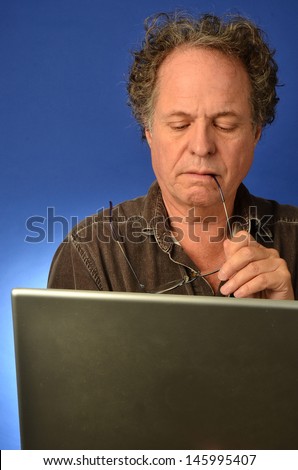 Senior man with expression looking at his computer/Older Man on Computer/Man is looking at his computer for emails and internet