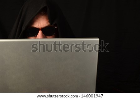 Suspicious man with sunglasses on computer/Identity Thief/Man with a black shroud on his computer