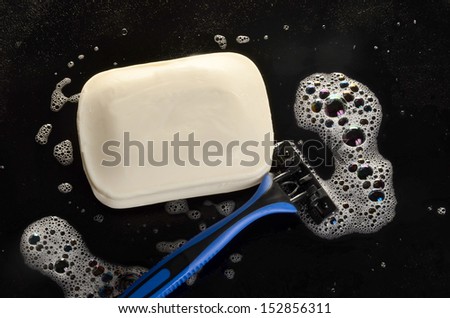 Razor and soap on a black surface/Morning Hygiene/Soap bubble surround soap bar and a razor