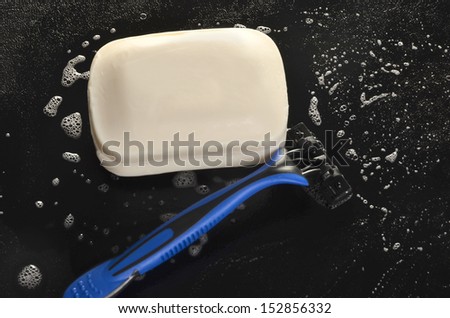 Razor and soap on a black surface/Morning Hygiene/Soap bubble surround soap bar and a razor