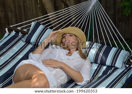 Woman on a enjoying her rest on a hammock/Woman on hammock/Beautiful woman resting on a hammock on a summer day