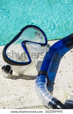 Blue snorkel resting on diving mask by a pool/Snorkel Gear/Snorkel equipment near a pool