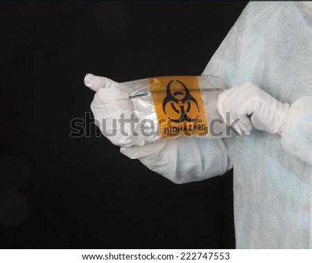 Technician holding a biohazard bag/Biohazard Technician/Person in a white protective garment holding a biohazard bag