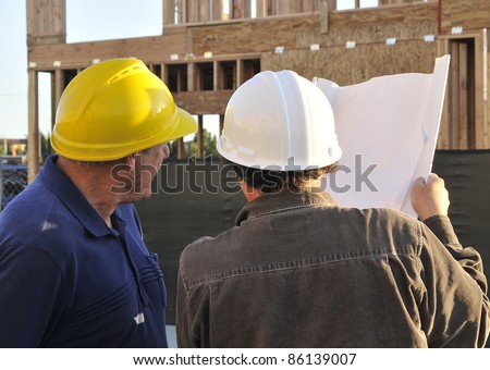 Two men working construction/Construction management/Two men with hard hats working at a construction sites