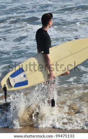 Surfer board and ocean/Surfs Up/Surfer wading into the ocean