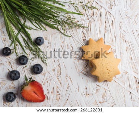 Berries, cookies and grass on wooden table