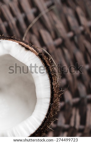 Half of coconut on wicker background, shallow FOD, focus on the edge of fruit