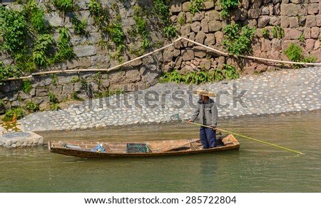 FENGHUANG - April 13:man collect rubbit in the river at Fenghuang ancient town on April 13, 2015 in Fenghuang,China.Fenghuang ancient town was added to UNESCO World Heritage Tentative List.