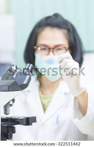 Short hair young female scientist analyzing and show microscope slide in medical lab