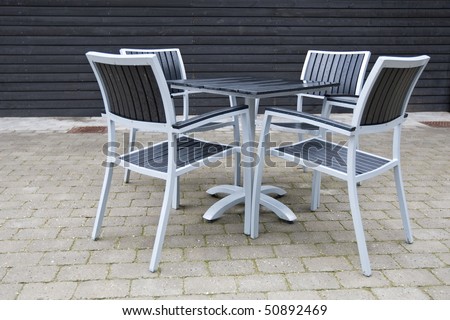 Grey and black chairs with table on a stone patio