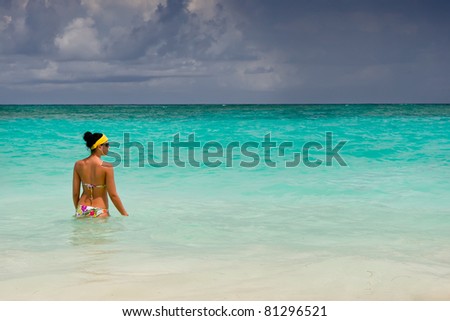 Tanned girls is standing in bright blue ocean under blue sky