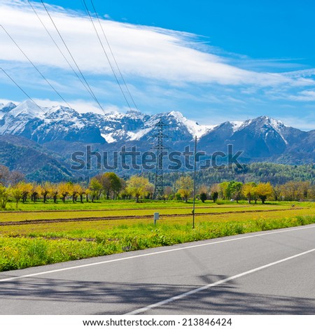 High-voltage Power Line in Piedmont on the Background of Snow-capped Alps