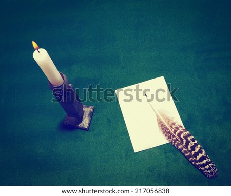 Burning Candle, a Sheet of Squared Paper and a Feather on the Green Table, Instagram Effect