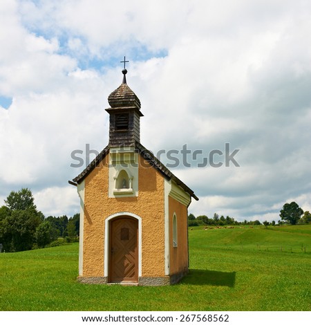 Christian Chapel in Southern Bavaria, against the Background of Clouds and Grazing Cows