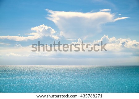 White clouds on blue sky over calm sea. Sunlight reflection on sea, Bali, Indonesia. Sunny sky with fantastic soft clouds and calm ocean, Bali. Summer outdoor nature. Summer serenity. Holiday vacation