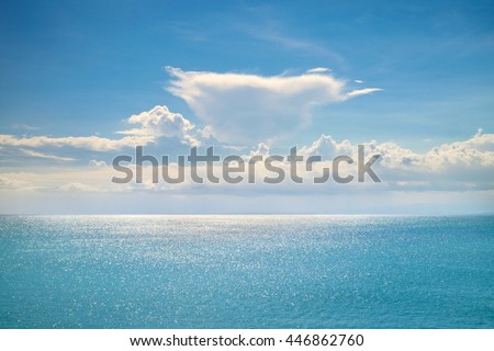 Fantastic white clouds on blue sky horizon. Calm ocean with sunlight reflection, Bali. Sunny sky clouds above blue ocean. Vibrant sunny sea and sky clouds. Amazing ocean. Tranquil Bali ocean serenity