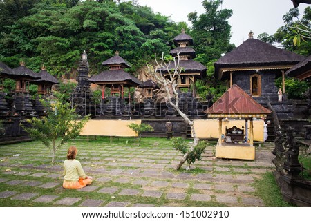 Woman sitting backwards - meditation while praying in Bali temple Pura Lempuyang Luhur during the religious ceremony in Indonesia. Meditation in Bali temple. Summer meditation in Bali. Indonesia, Bali