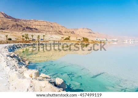 Dead Sea coastline with white salt beach and mountains at sunny day in Ein Bokek, Israel. White mineral salt beach at Dead sea, Israel. Dead sea landscape of Israel. Mineral water of Dead sea, Israel
